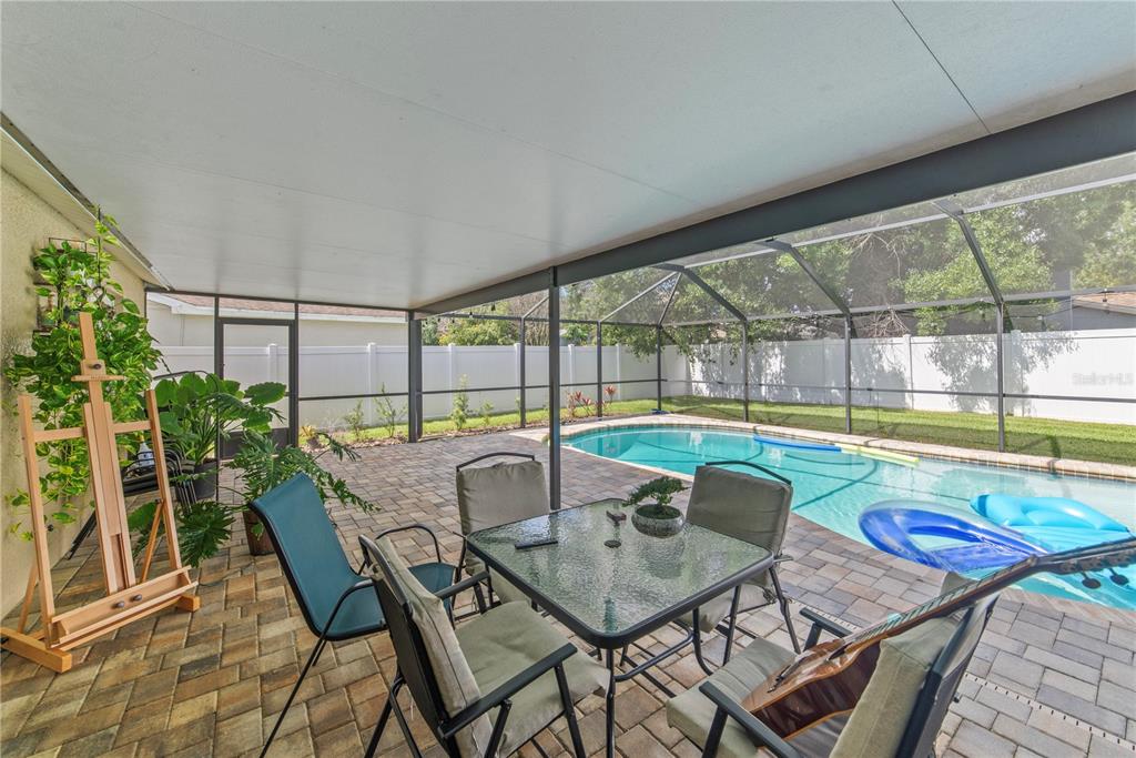 A covered patio with a dining set, potted plants, and a screened-in swimming pool — 1003 RED OAK CIRCLE, BRANDON, FL
