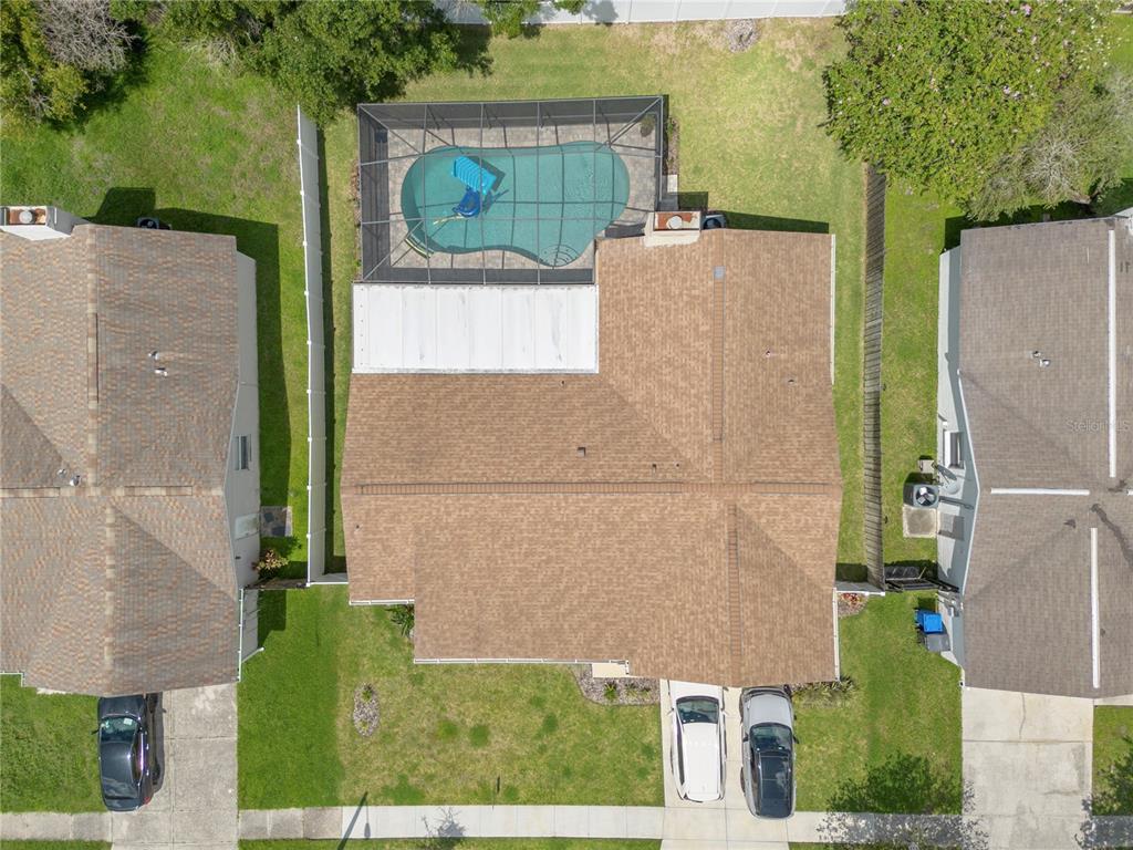 An aerial view shows a house with a brown roof, a pool enclosure, and driveway — 1003 RED OAK CIRCLE, BRANDON, FL