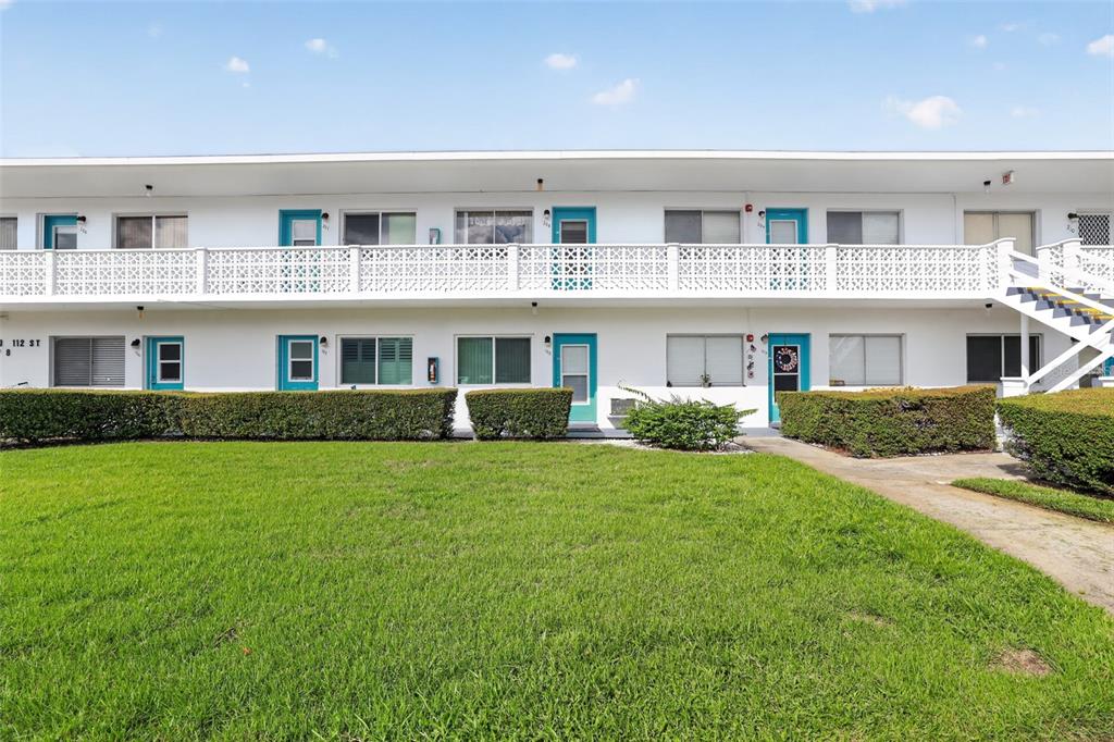 A two-story apartment building with a white exterior, blue doors, and a green lawn — 8320 112TH STREET UNIT 208, SEMINOLE, FL