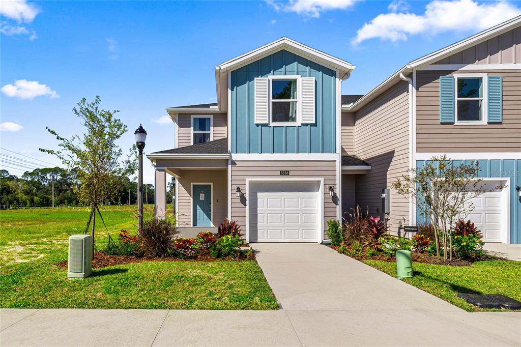A two-story townhouse with a blue-accented facade, a single-car garage, and a concrete driveway — 14585 NW 163RD PLACE, ALACHUA, FL