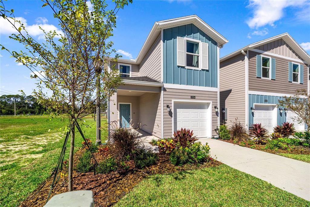 A two-story house with a blue vertical-siding accent, a single-car garage, and a front porch — 14585 NW 163RD PLACE, ALACHUA, FL