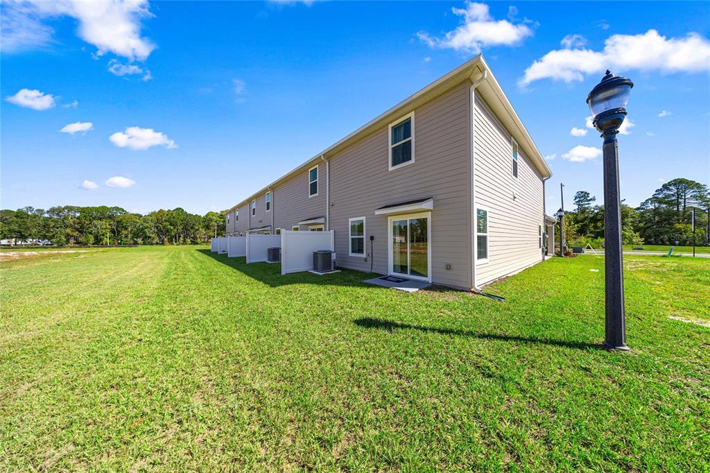 A side view of a multi-unit townhouse with beige siding and a grassy yard — 14585 NW 163RD PLACE, ALACHUA, FL