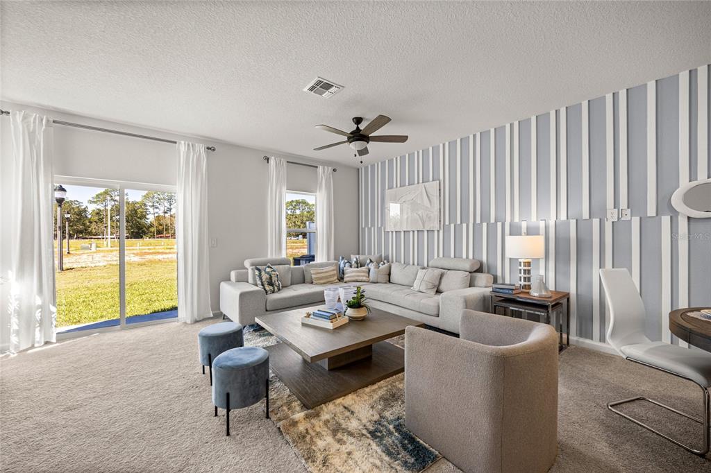 A living room features a sectional sofa, a coffee table, and a striped accent wall — 14585 NW 163RD PLACE, ALACHUA, FL