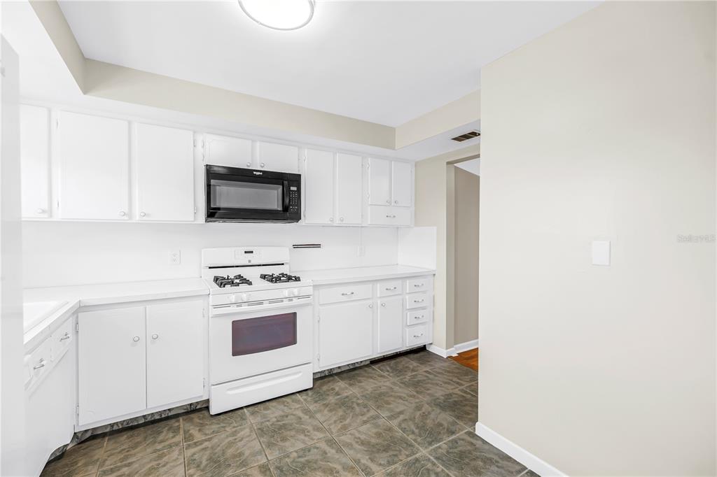 A kitchen with white cabinets, white appliances, and dark tiled flooring — 1868 SHORE DRIVE S UNIT 310, SOUTH PASADENA, FL