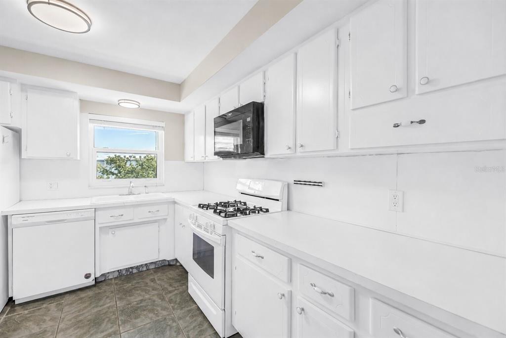 A kitchen with white cabinets, white appliances, a gas range, and dark tile flooring — 1868 SHORE DRIVE S UNIT 310, SOUTH PASADENA, FL