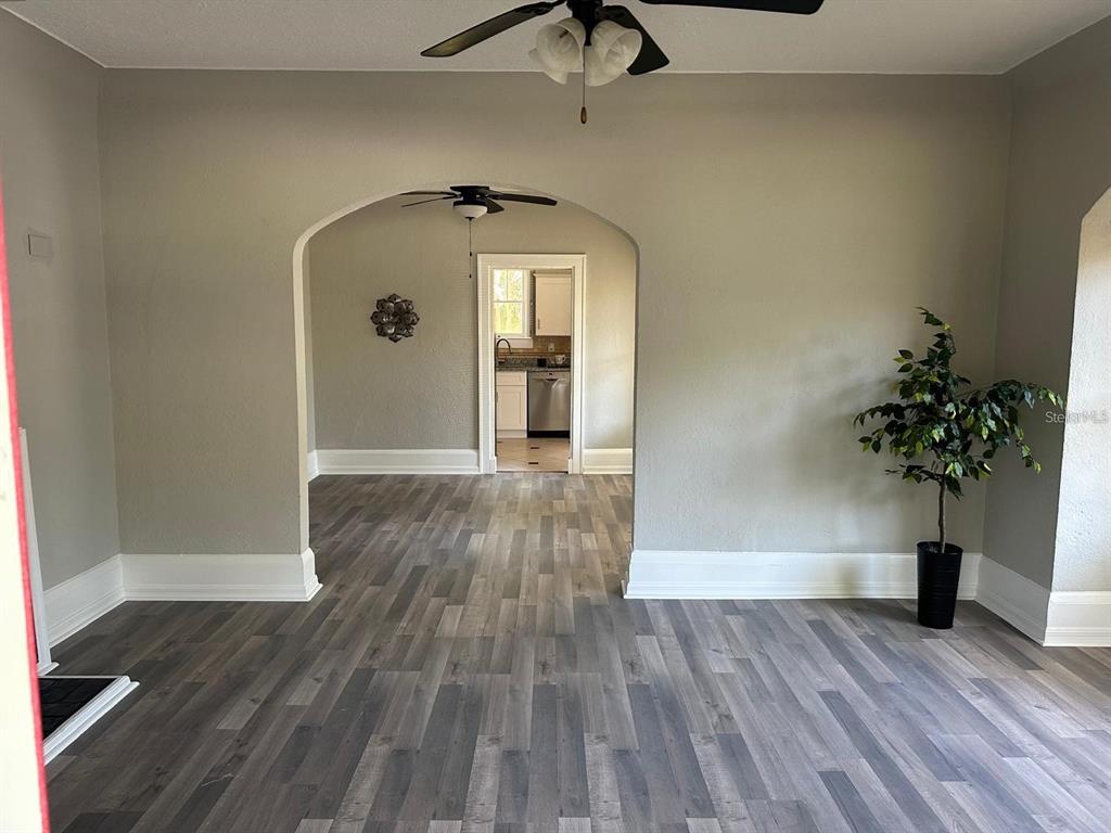 An arched doorway connects a living area with wood-look flooring to a kitchen beyond — 221 N JULIA AVENUE, DELAND, FL