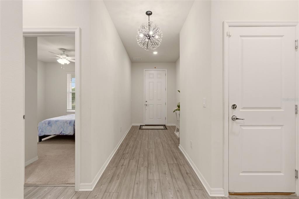 A white marble console table sits in a hallway with a sunburst mirror and plant — 4120 RAINFALL PLACE, SANFORD, FL