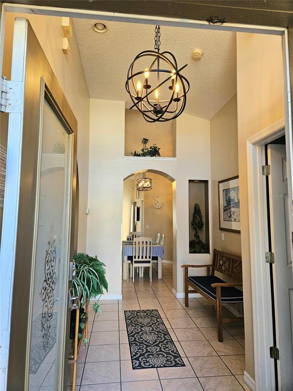 A screened-in pool area features a swimming pool, lounge chairs, and palm trees — 2914 BLOOMING ALAMANDA LOOP, KISSIMMEE, FL