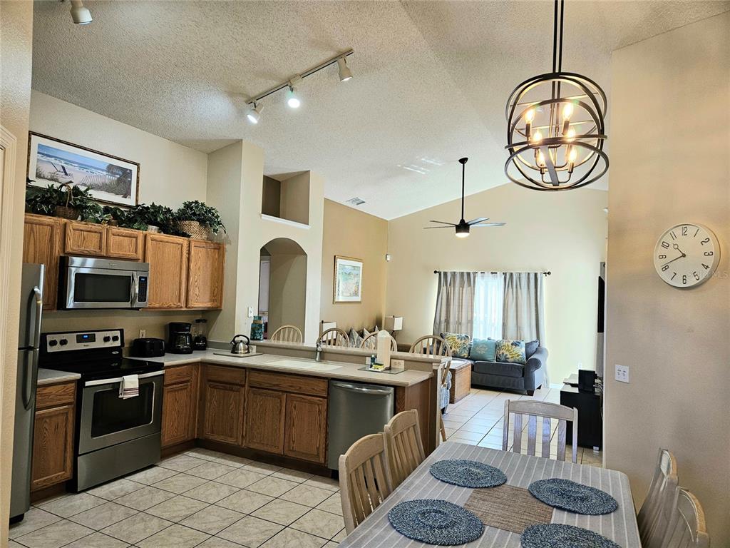 A tiled entryway features a spherical chandelier, a wooden bench, and an arched doorway — 2914 BLOOMING ALAMANDA LOOP, KISSIMMEE, FL