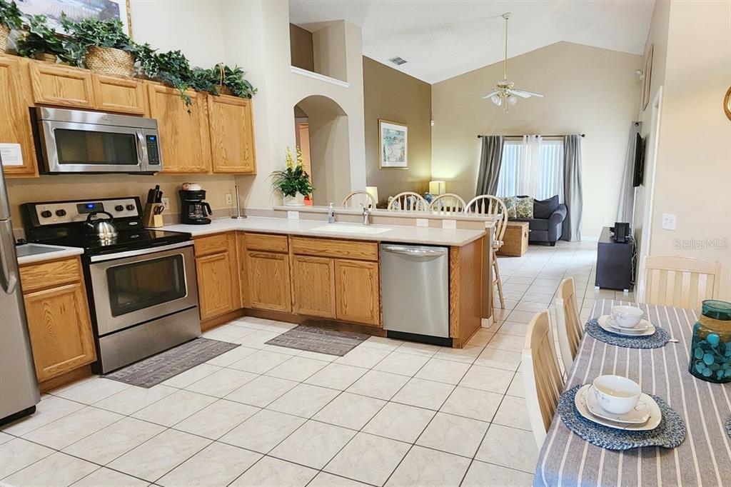 A living room with tile floors, a gray sofa, a tan sofa, and a breakfast bar — 2914 BLOOMING ALAMANDA LOOP, KISSIMMEE, FL