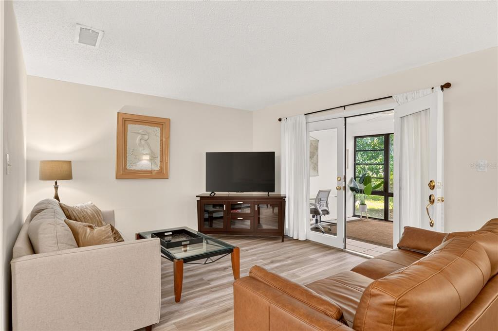 A living room with a tan sofa, brown leather couch, television, and glass sliding doors — 2842 SW 14TH DRIVE UNIT 103, GAINESVILLE, FL