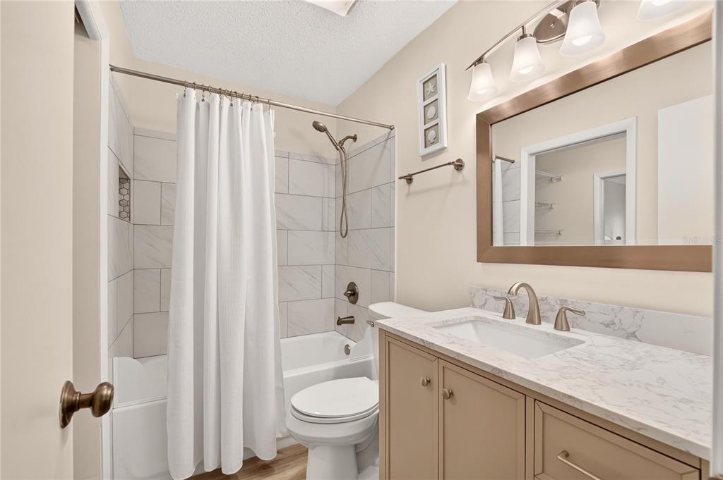 A bathroom features a vanity with a marble countertop, a toilet, and a tiled shower-tub — 2842 SW 14TH DRIVE UNIT 103, GAINESVILLE, FL