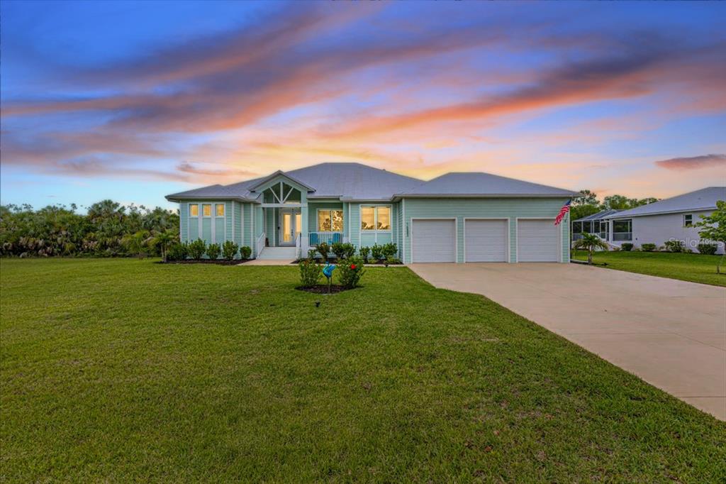 A light green single-story house with a three-car garage and a large front lawn — 16883 ACAPULCO ROAD, PUNTA GORDA, FL