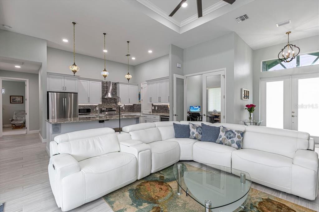A white sectional sofa sits in a living room with an open kitchen and high ceilings — 16883 ACAPULCO ROAD, PUNTA GORDA, FL
