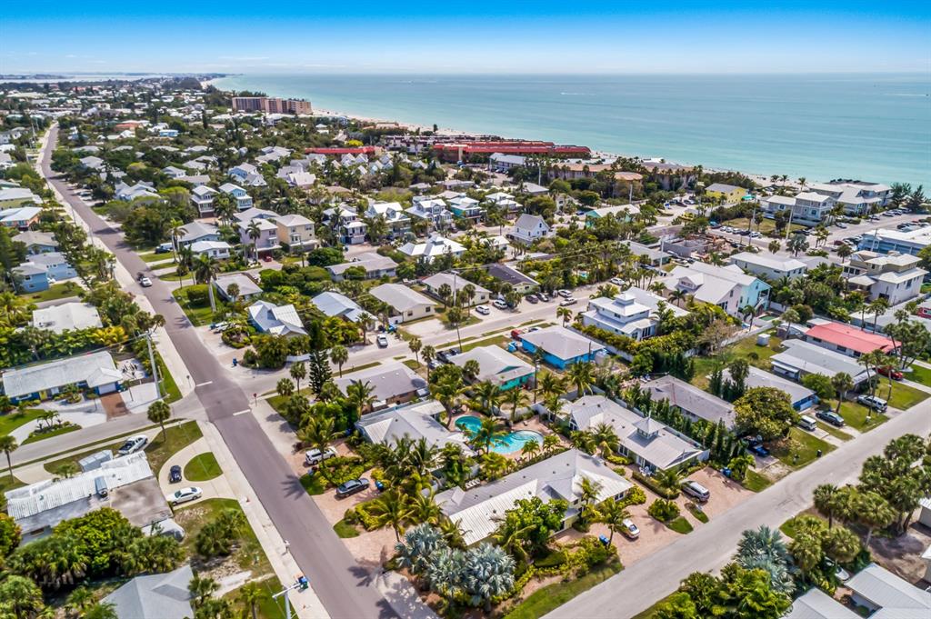 An aerial view shows a coastal neighborhood with houses, palm trees, and a swimming pool — 6606 HOLMES BOULEVARD UNIT 3, HOLMES BEACH, FL