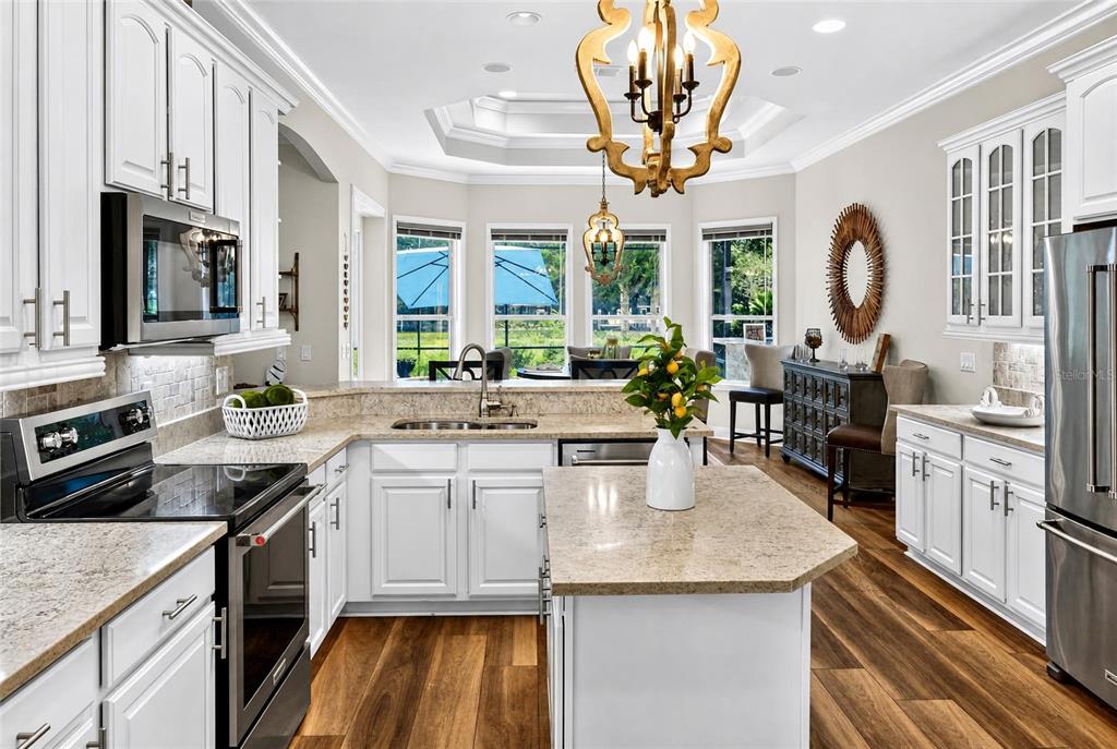 A white kitchen features granite countertops, stainless steel appliances, and a large central island — 101 LONGVIEW WAY N, PALM COAST, FL