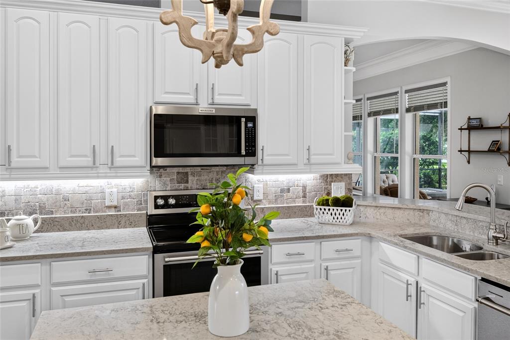 A kitchen features white cabinets, stone countertops, a tile backsplash, and a central island — 101 LONGVIEW WAY N, PALM COAST, FL