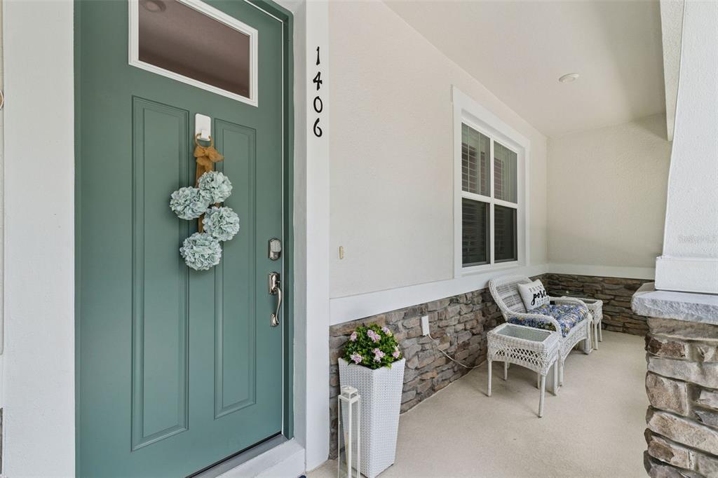 A front porch features a teal door, stone siding, and white wicker furniture — 1406 BLUMBERG BOULEVARD, WINTER SPRINGS, FL