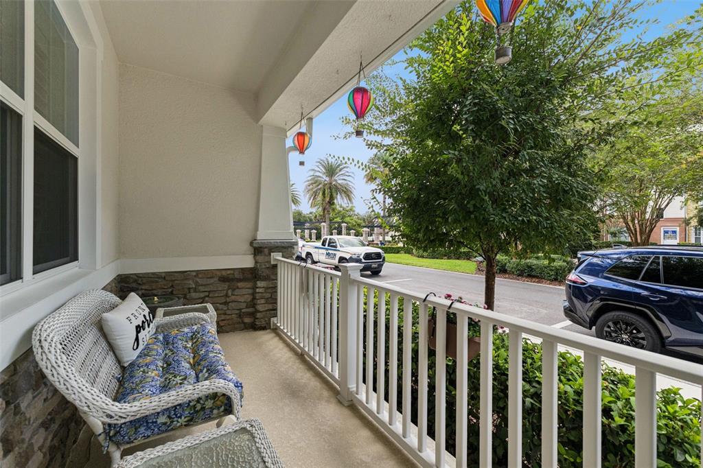 A covered front porch features white wicker furniture, stone accents, and hanging hot air balloon decorations — 1406 BLUMBERG BOULEVARD, WINTER SPRINGS, FL
