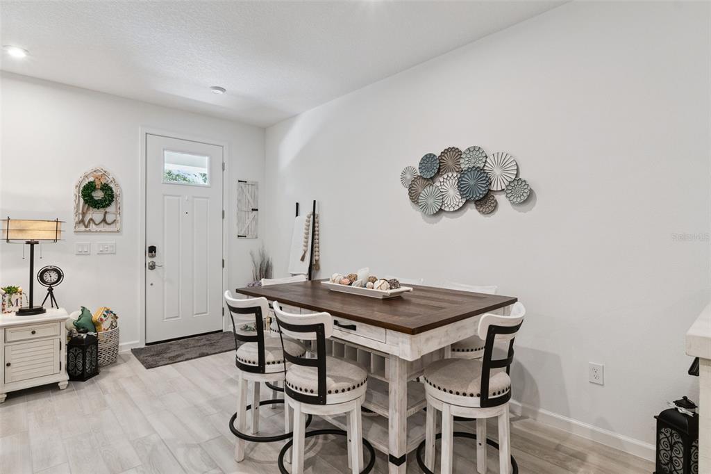 A dining area features a wooden table with four chairs, white walls, and a front door — 1406 BLUMBERG BOULEVARD, WINTER SPRINGS, FL
