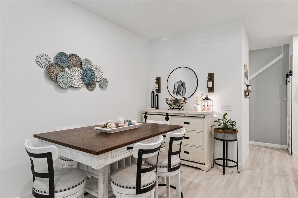 A dining room features a wooden table, white chairs, a sideboard, and wall-mounted circular decor — 1406 BLUMBERG BOULEVARD, WINTER SPRINGS, FL