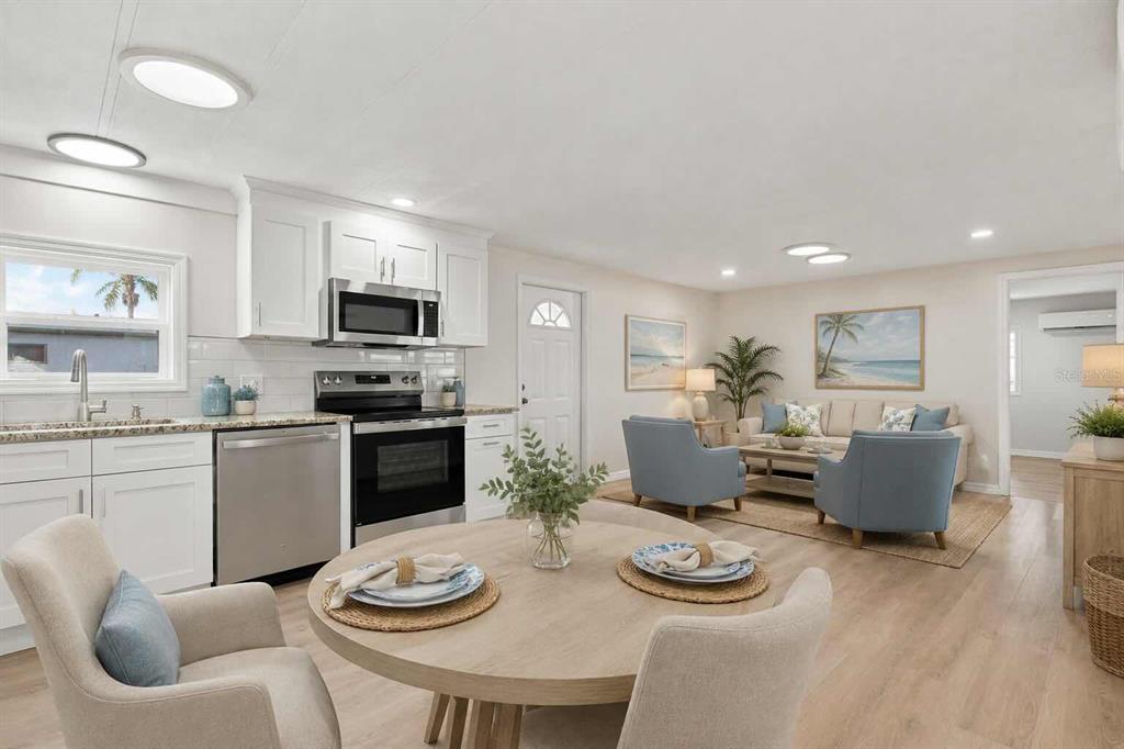 A bright, empty room features white walls, light wood-look flooring, two windows, and a wall-mounted AC — 6711 CLEMENS BOULEVARD, PORT RICHEY, FL