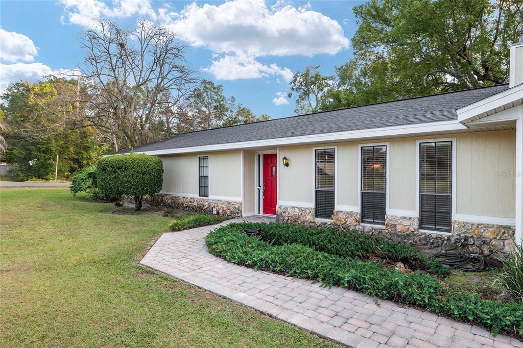 A single-story house with light siding, stone accents, and a bright red front door — 3300 SE 32ND STREET, OCALA, FL