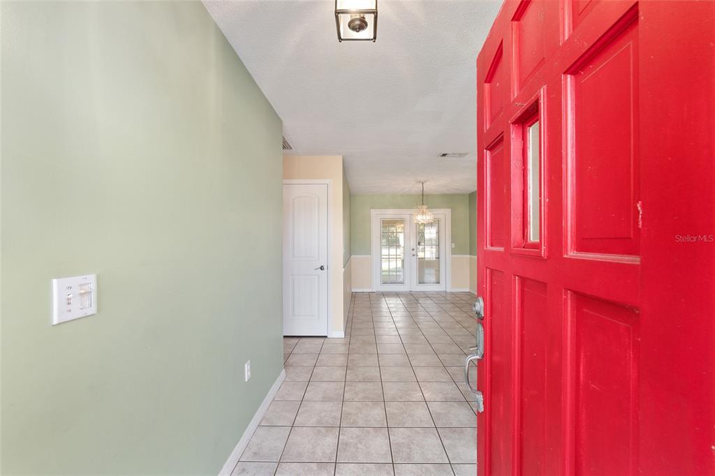 An entryway with a red door opens into a tiled room with green walls — 3300 SE 32ND STREET, OCALA, FL