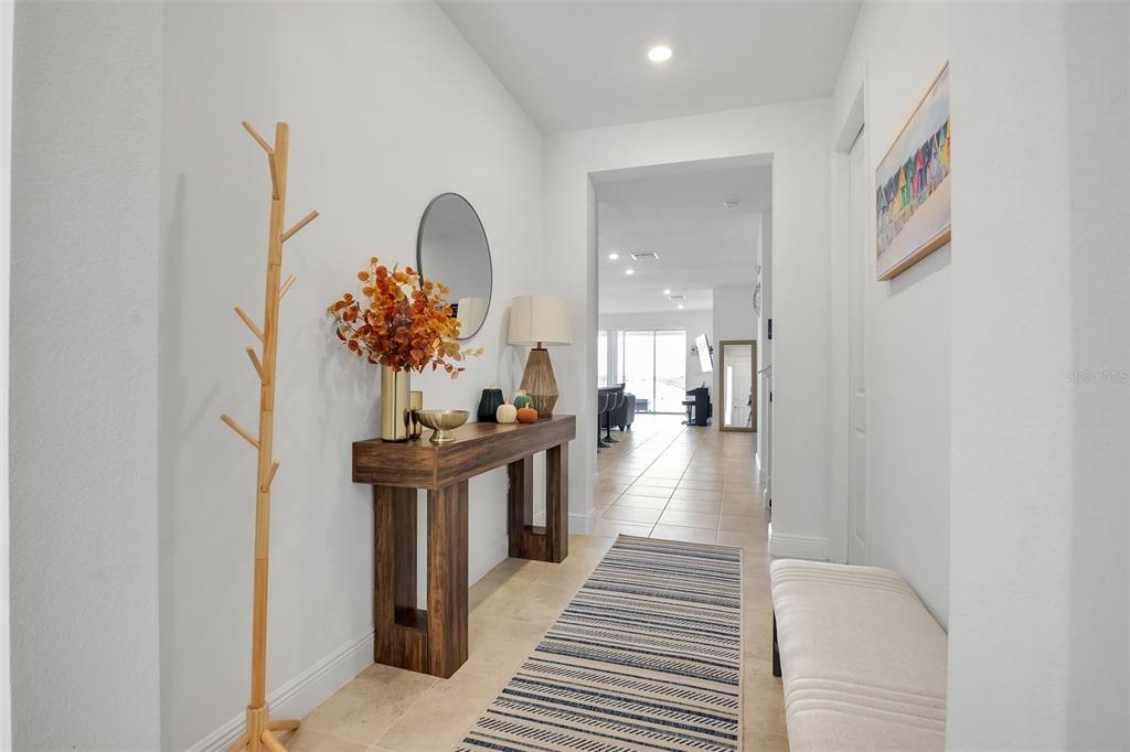 A bright entryway features a wooden console table, a coat rack, and a striped rug — 2100 KEYSTONE CIRCLE, MINNEOLA, FL