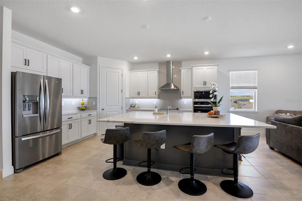 A modern kitchen features white cabinetry, a large dark gray island, and stainless steel appliances — 2100 KEYSTONE CIRCLE, MINNEOLA, FL