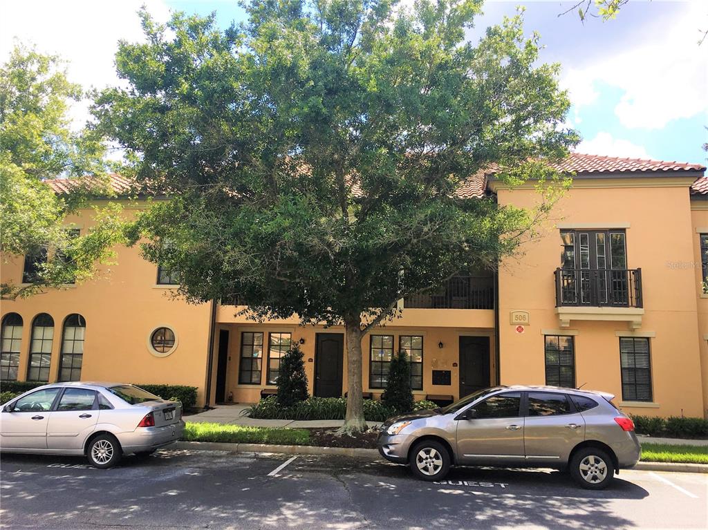 A two-story tan stucco building with a tile roof and a large tree in front — 506 MIRASOL CIRCLE UNIT 101, CELEBRATION, FL