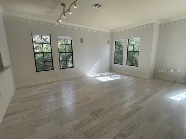 An empty room with light wood flooring, neutral walls, and four windows overlooking trees — 506 MIRASOL CIRCLE UNIT 101, CELEBRATION, FL
