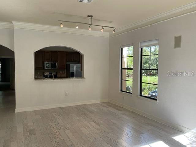 An interior view of a dining area with light wood floors, arched opening, and track lighting — 506 MIRASOL CIRCLE UNIT 101, CELEBRATION, FL