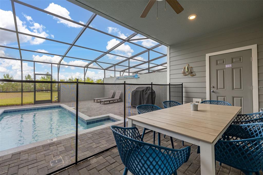 A covered patio features a dining set, a pool safety fence, and a screened-in pool — 971 PARADISE DRIVE, DAVENPORT, FL