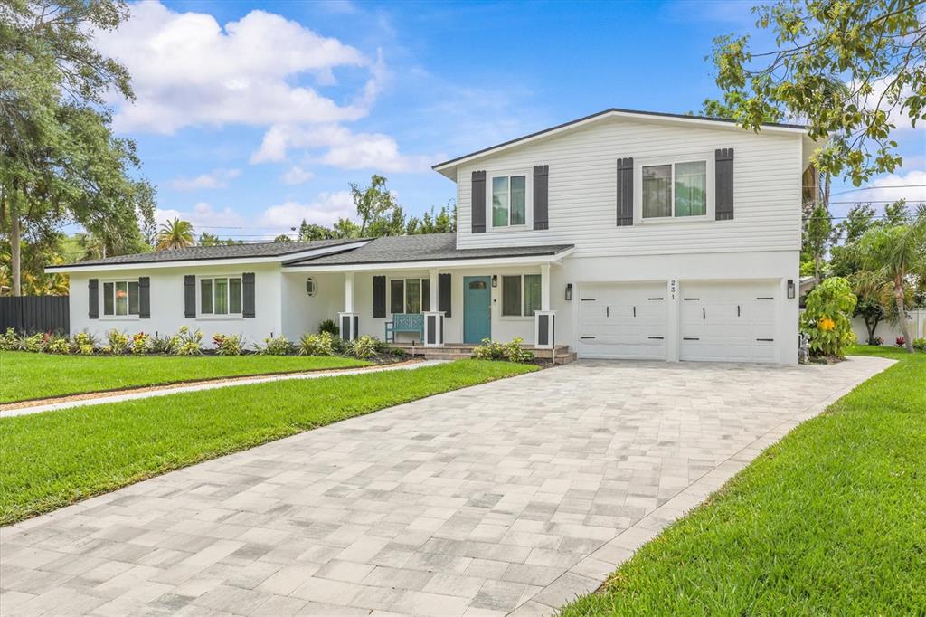 A two-story white house with a paved driveway, blue front door, and green lawn — 231 LIME CIRCLE S, DUNEDIN, FL