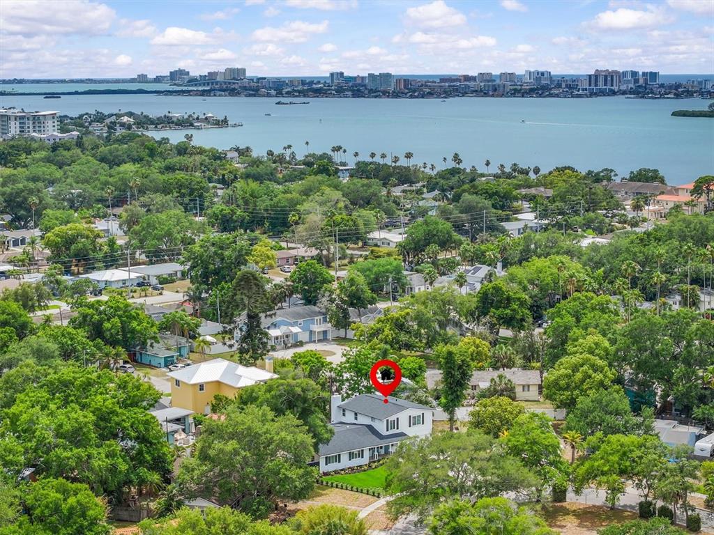 An aerial view shows a white house with a dark roof surrounded by lush trees — 231 LIME CIRCLE S, DUNEDIN, FL
