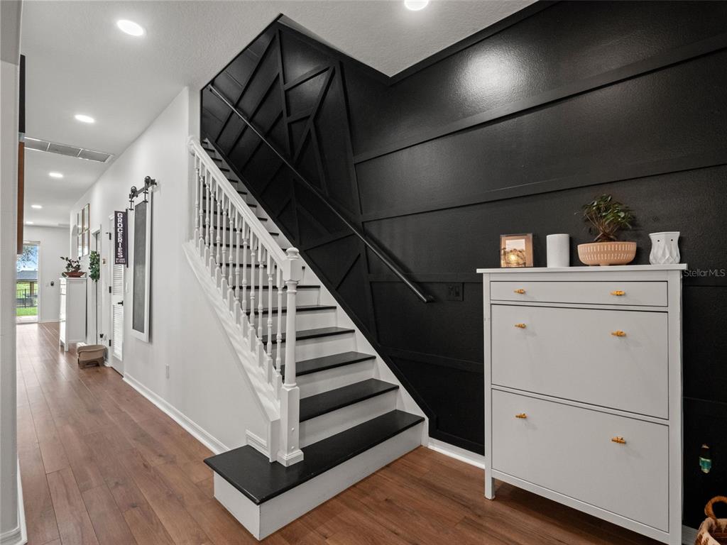 A staircase with black treads and white railings sits beside a black accent wall — 720 BAREFOOT BAY LOOP, GROVELAND, FL