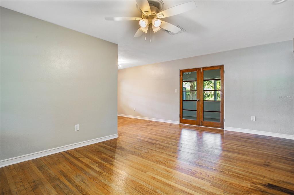An empty room features hardwood floors, light gray walls, a ceiling fan, and French doors — 1955 ELAND AVENUE, WINTER PARK, FL