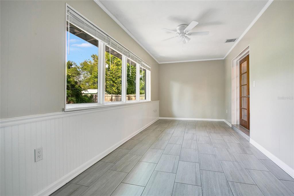 A sunroom with gray tile flooring, white beadboard wainscoting, a ceiling fan, and large windows — 1955 ELAND AVENUE, WINTER PARK, FL