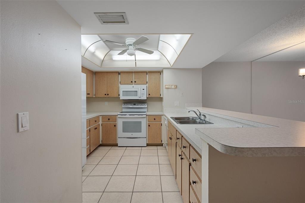 A kitchen features light wood cabinets, white appliances, tile flooring, and a recessed ceiling light — 3 CYPRESS RUN UNIT 35A, HOMOSASSA, FL
