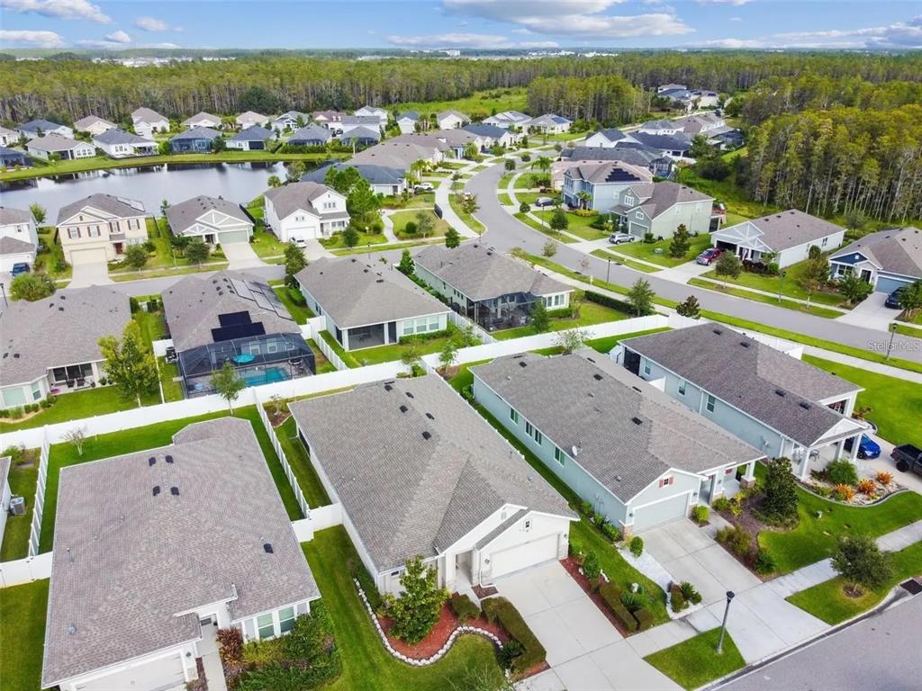An aerial view shows a suburban neighborhood with single-family homes, paved streets, and a pond — 2776 SATILLA LOOP, ODESSA, FL