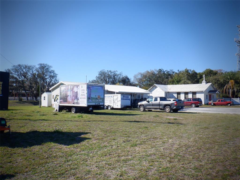 A grassy lot features a white building, a parked box truck, and a pickup truck — 2239 OLD GUNN HIGHWAY, ODESSA, FL