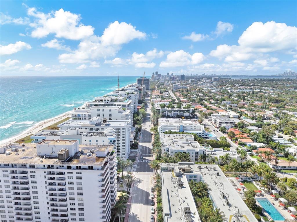 An aerial view shows high-rise buildings along a coastline next to a city street — 9201 COLLINS AVENUE UNIT 821, SURFSIDE, FL