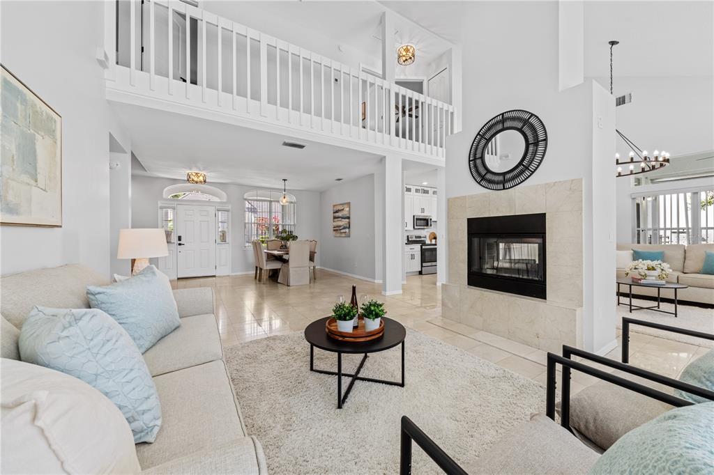 A bright living room features a fireplace, a lofted balcony, and an open floor plan — 130 WIMBLEDON CIRCLE, LAKE MARY, FL