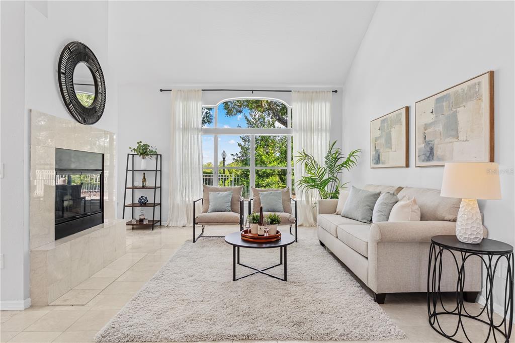 A bright living room features a fireplace, large windows, a sofa, and two armchairs — 130 WIMBLEDON CIRCLE, LAKE MARY, FL