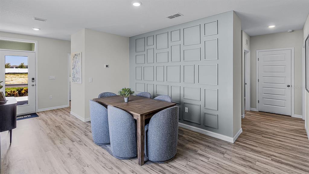 A dining area features a wooden table, blue chairs, and a light blue paneled accent wall — 5584 TAVERNA LOOP, WINTER HAVEN, FL