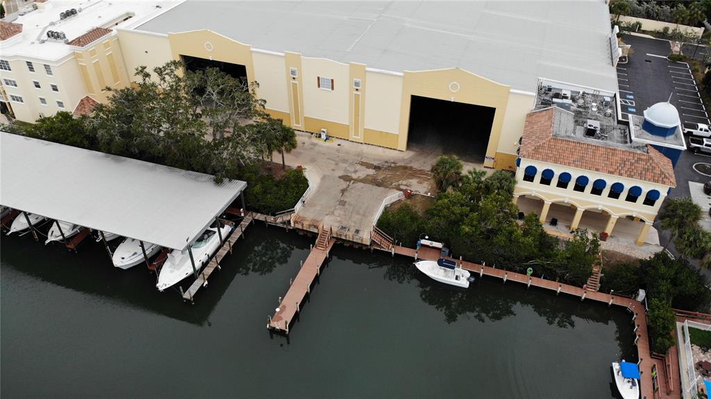 An aerial view shows a large warehouse building with boat slips and a private dock — 570 BLACKBURN POINT ROAD UNIT 36, OSPREY, FL