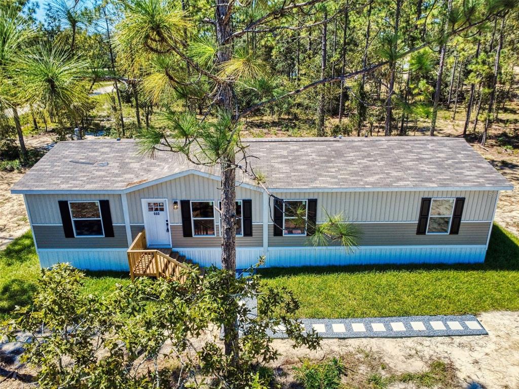 An aerial view of a single-story manufactured home with tan and white siding and shutters — 660 NE 131 AVENUE, WILLISTON, FL