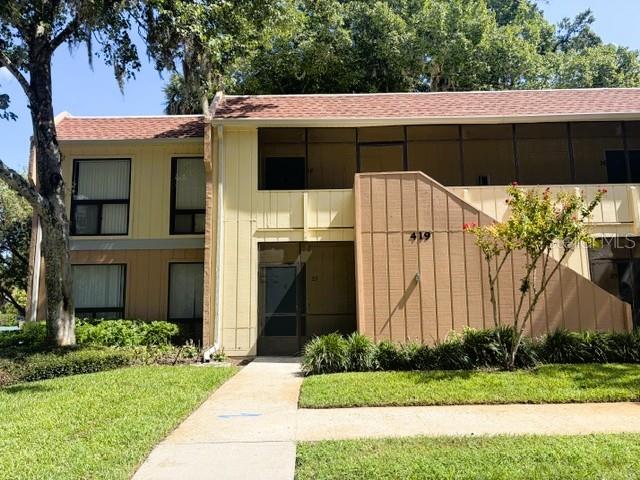 A two-story apartment building with tan siding, a screened balcony, and a concrete walkway — 419 SHEOAH BOULEVARD UNIT 28, WINTER SPRINGS, FL