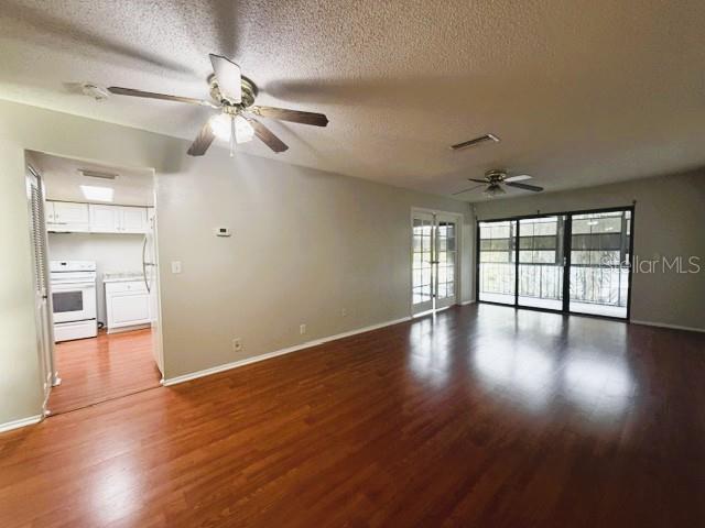 A living room with wood-look flooring, two ceiling fans, and an adjacent kitchen — 419 SHEOAH BOULEVARD UNIT 28, WINTER SPRINGS, FL
